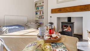 Una habitación acogedora con chimenea, una estantería y una mesa de comedor con comida y bebidas.