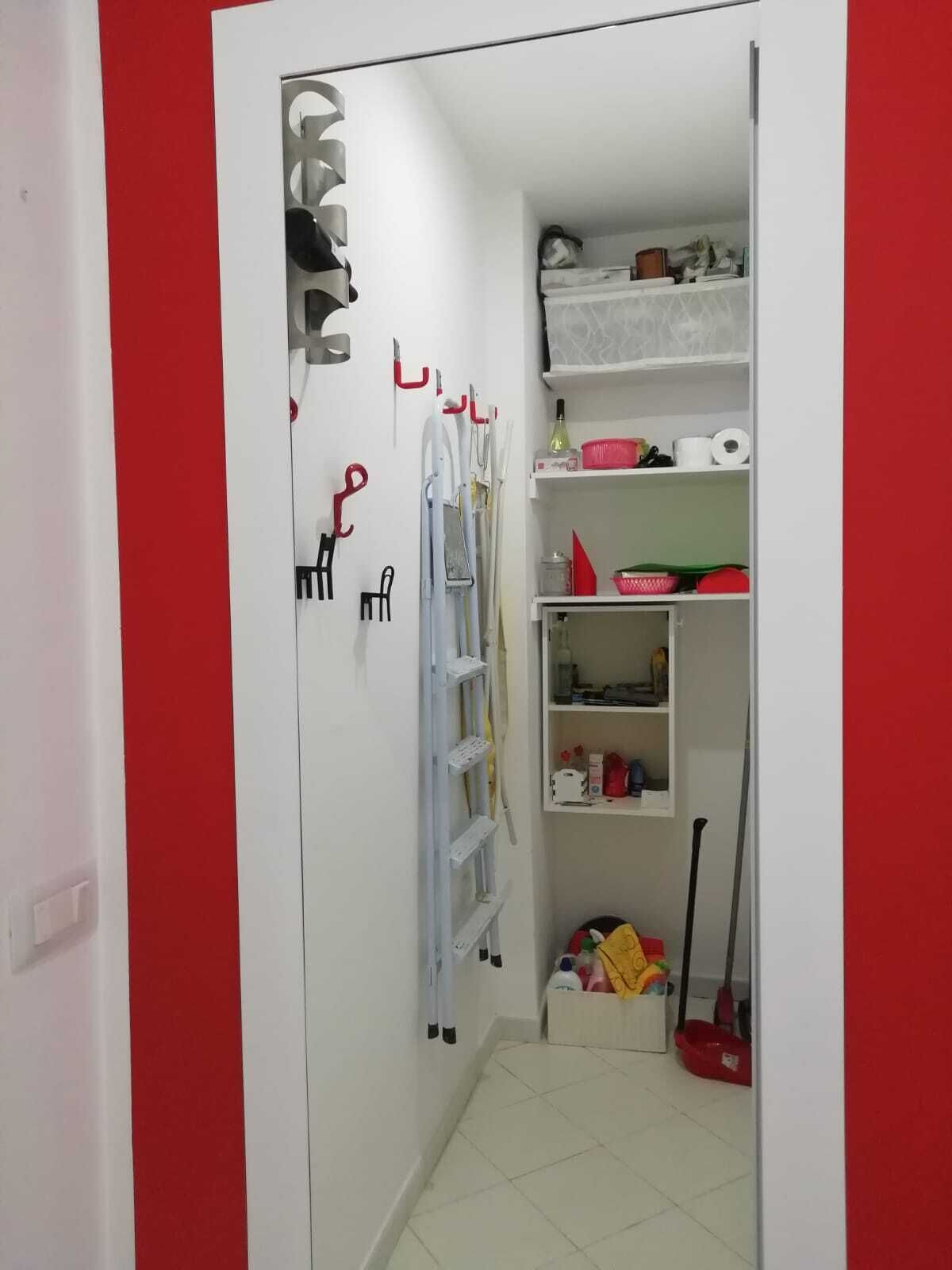 A narrow hallway with a white door, a red wall, and a white door frame.