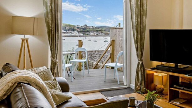 Un salón con sofá, televisión y vistas a un puerto con barcos.