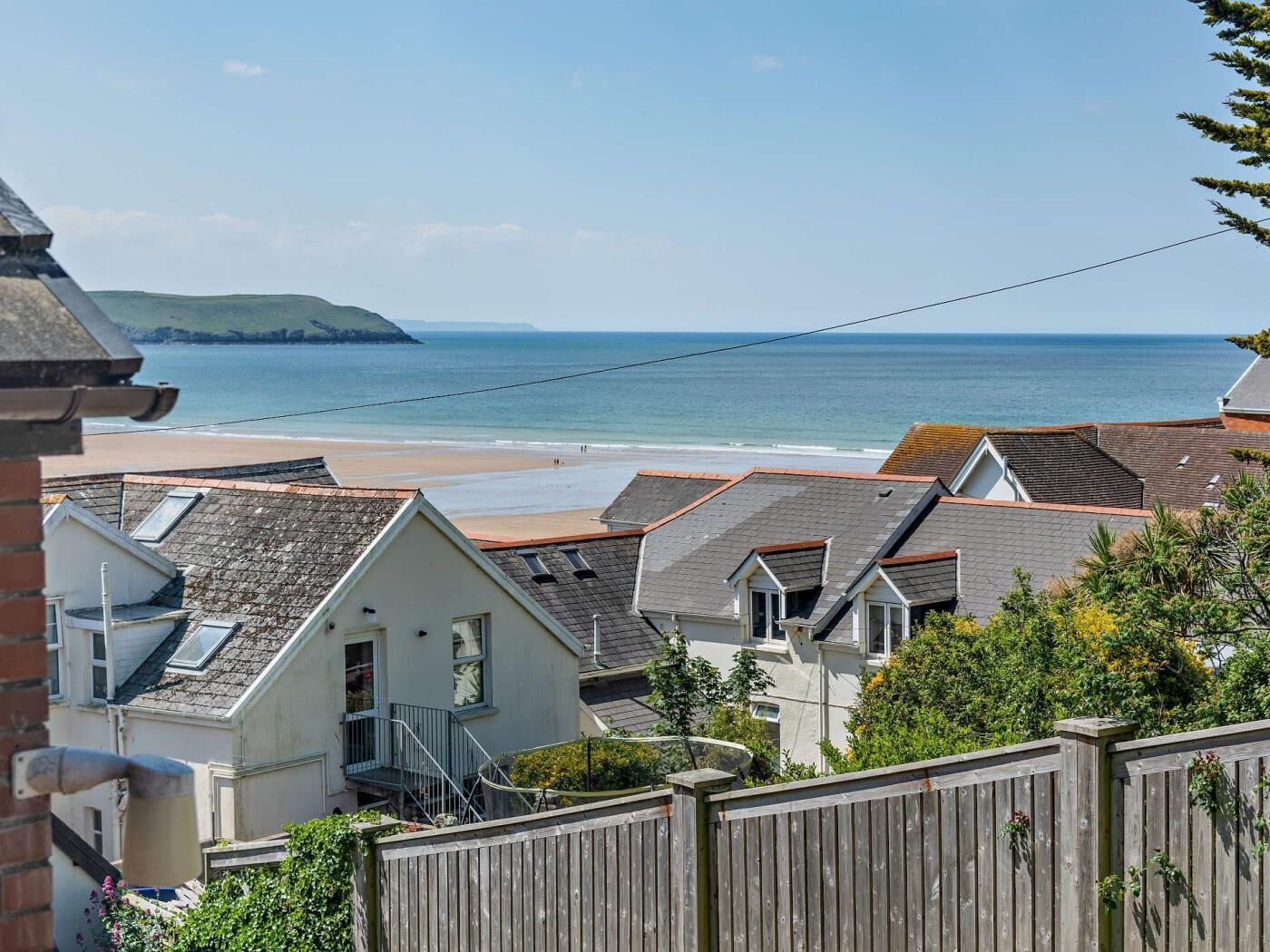 A coastal residential area with houses, a beach, and a clear sky.