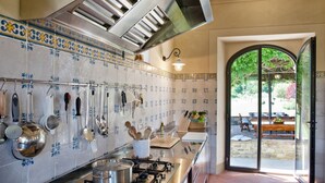 Uma cozinha com utensílios pendurados, um fogão e vista para um pátio externo.