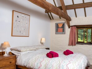 A bedroom with a bed, two bedside lamps, a framed picture, a window with curtains, and a wooden ceiling beam. - 1 Bed in Crickhowell (oc-bn079) (Llangynidr)