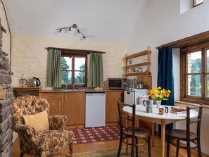 A cozy kitchen with wooden cabinets, a microwave, a coffee maker, and a dining area with a table and chairs. - 1 Bed in Crickhowell (oc-bn079) (Llangynidr)