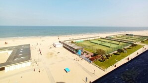 Blick auf einen Strand mit Tennisplatz und einem Gebäude mit flachem Dach.