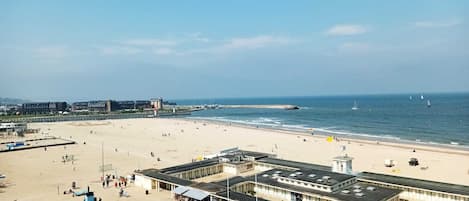A beach with a boardwalk, beach umbrellas, and a building with a sign.