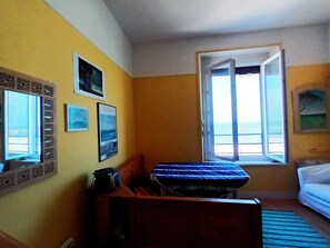 Ett rum med en säng, ett skrivbord, ett fönster med utsikt och dekorationer på väggarna.