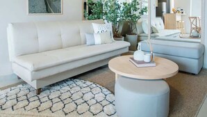 A modern living room with a white sofa, a round coffee table, and a large mirror. - Corporate Stays Insignia City - A44 (Asunción)