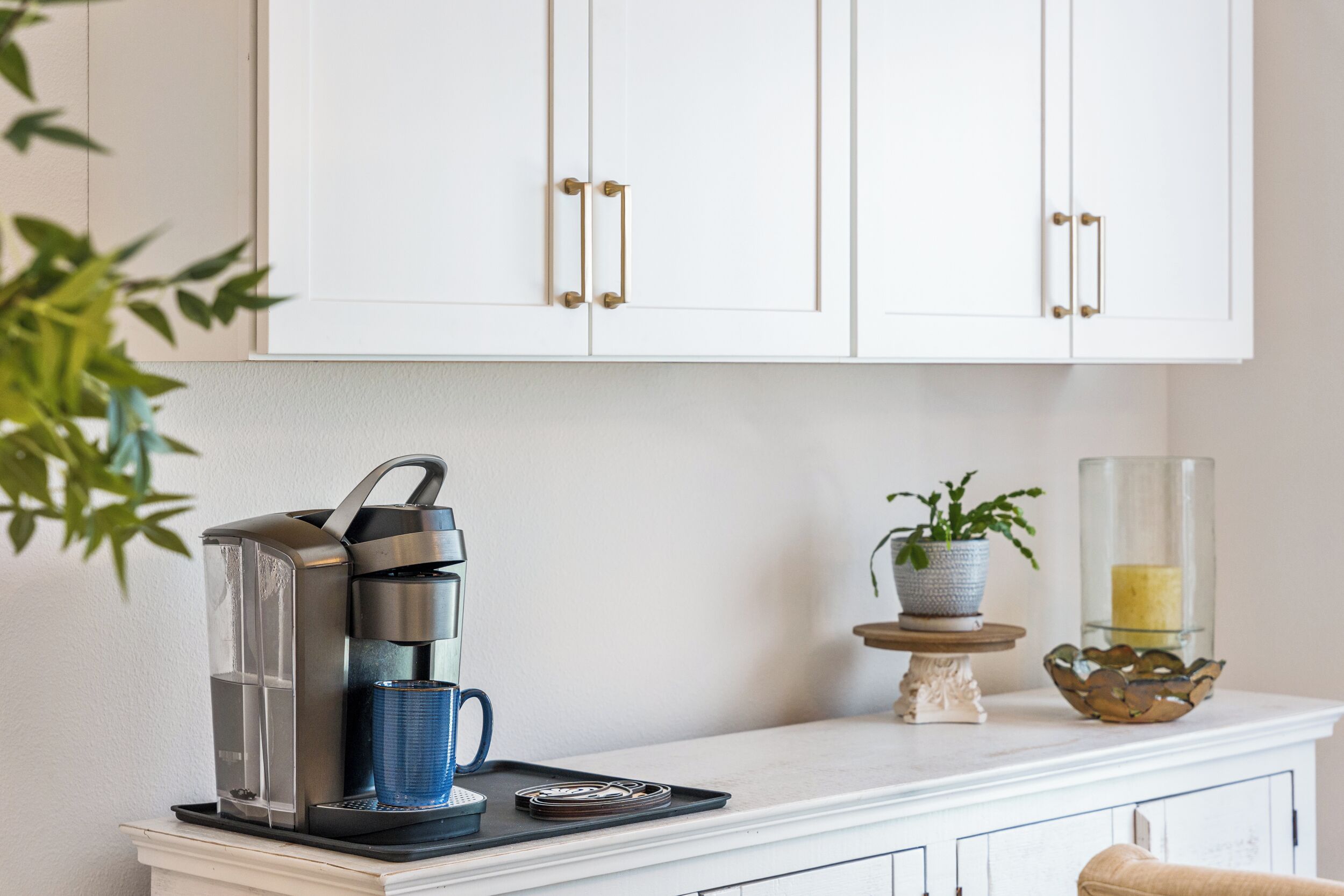 A kitchen with a coffee maker, a potted plant, and a candle holder on the counter.