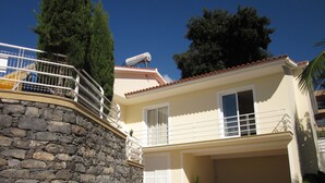 Ein zweistöckiges Haus mit Steinmauer, Garage und Satellitenschüssel.