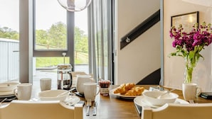 Una mesa de desayuno con café, croissants y un jarrón de flores.