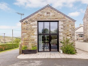 Un bâtiment en pierre doté d’une grande porte vitrée et d’une petite fenêtre située au-dessus.