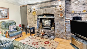 A living room with a stone fireplace, leather sofa, and a flat-screen TV. - 2 Bed in Brecon (oc-bn138) (Bwlch)