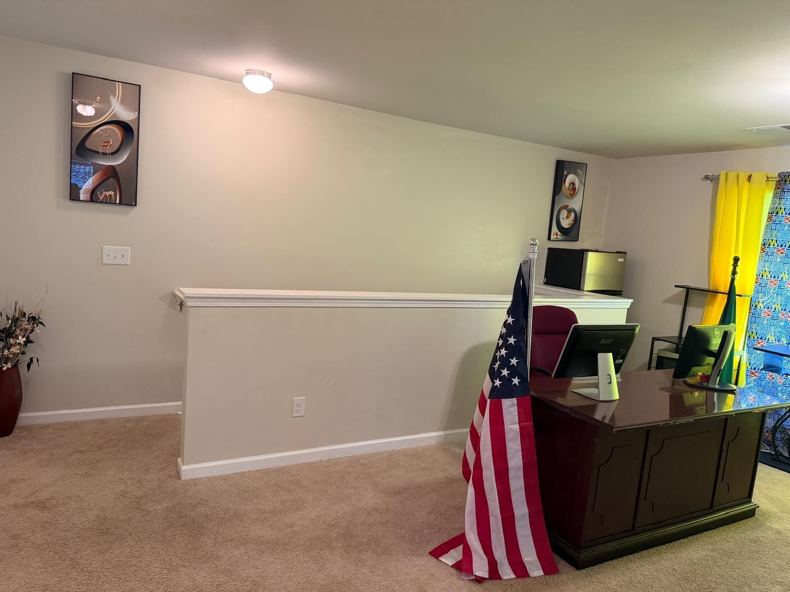 A room with a desk, computer, and an American flag.