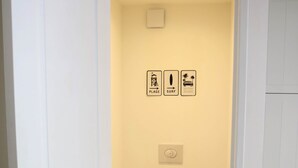 Un baño con inodoro, dispensador de papel higiénico y secamanos.