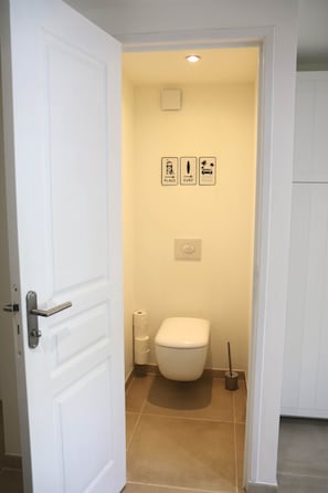 Ein Badezimmer mit Toilette, Toilettenpapierhalter und einem Handtrockner.