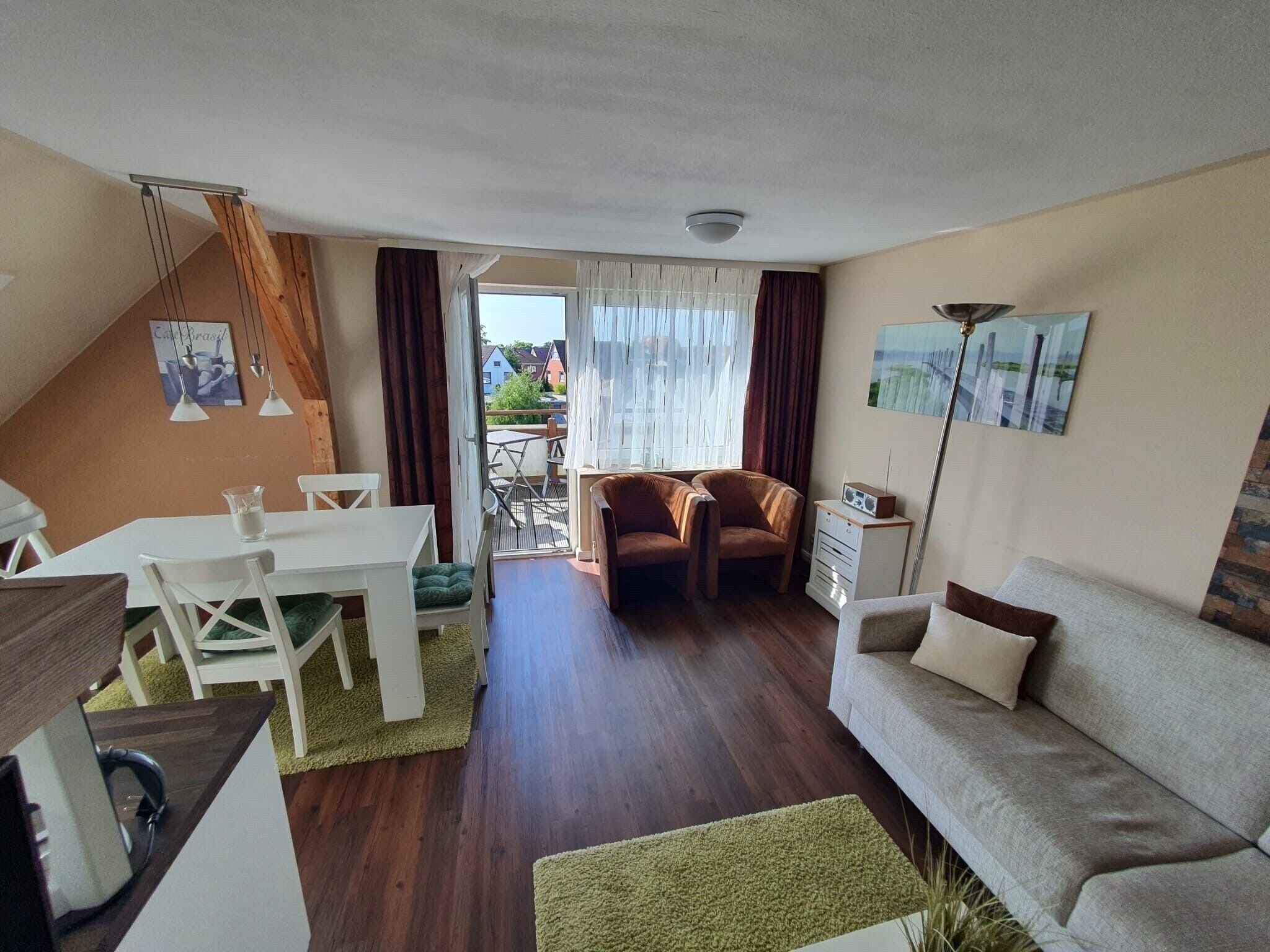Een woonkamer met een bank, stoelen, een eettafel en uitzicht door een glazen deur.