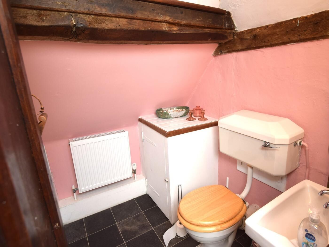 A small bathroom with a toilet, a sink, a radiator, and a cabinet.