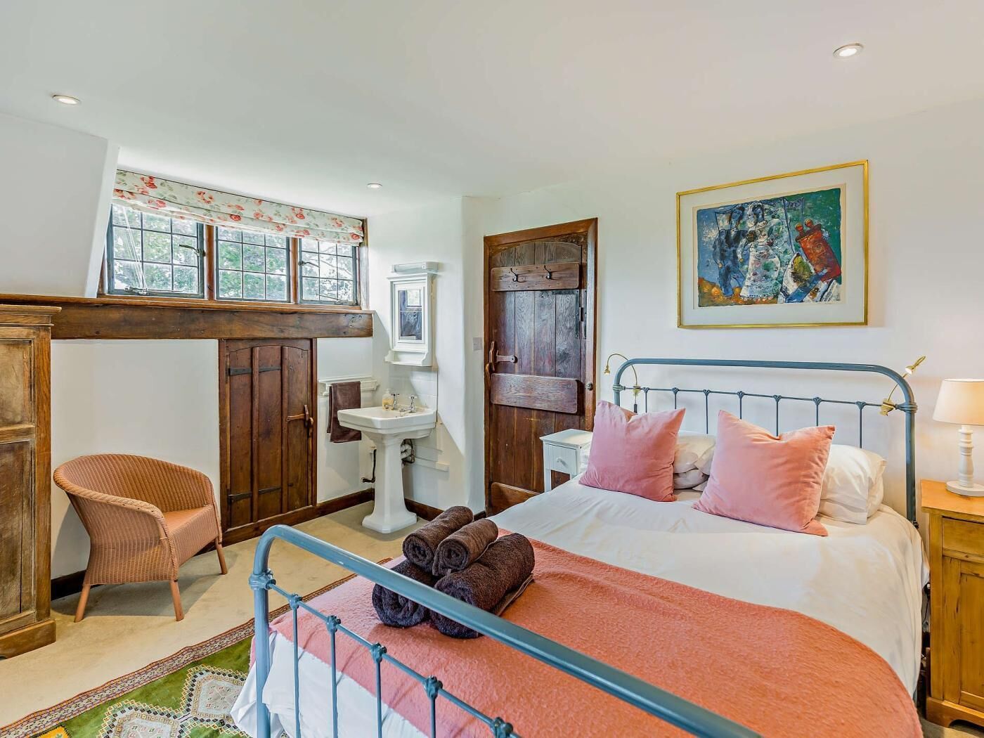 A bedroom with a bed, a chair, a sink, and a door.