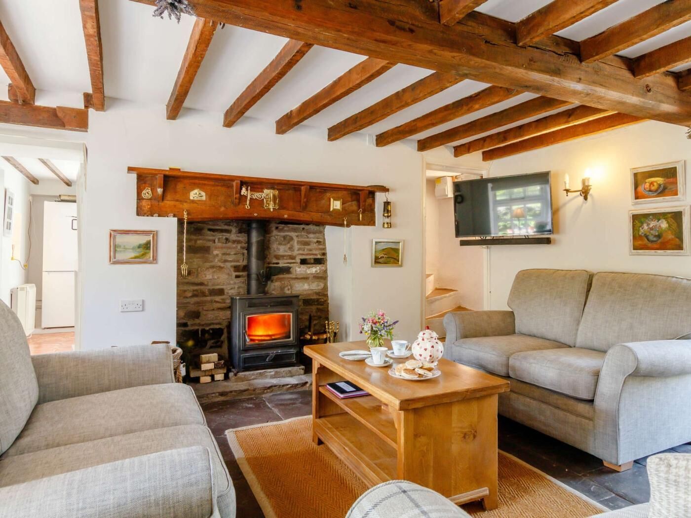 A cozy living room with a fireplace, a sofa, a television, and a wooden coffee table.