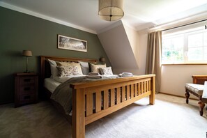 Ein Schlafzimmer mit einem hölzernen Bett, einem Nachttisch, einer Lampe, einem Fenster mit Vorhängen und einem Gemälde an der Wand.