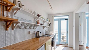 Une cuisine moderne avec un dosseret de carrelage blanc, des étagères en bois et une vue sur l’extérieur.