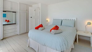 Une chambre à coucher avec un lit, une armoire, un miroir et une table de chevet.