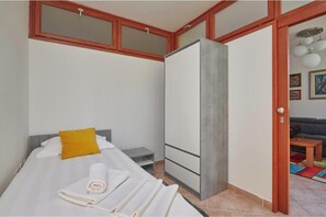 Ein Schlafzimmer mit einem Bett, einem Kleiderschrank, einem kleinen Tisch und einer Tür zu einem Wohnbereich.