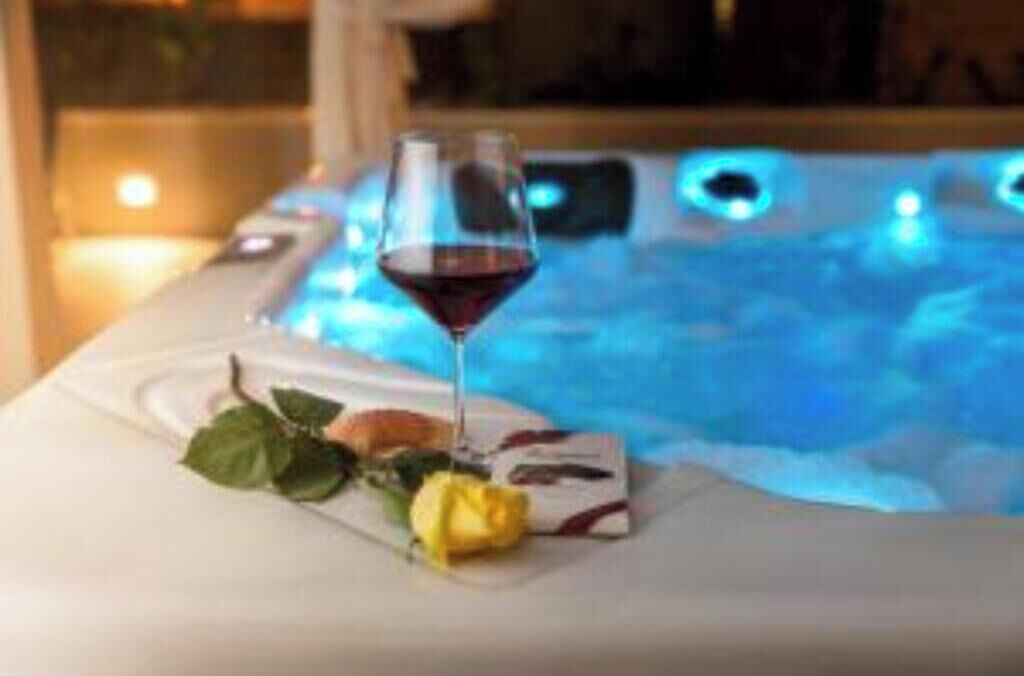 Ein Whirlpool mit einem Glas Rotwein und einer Rose auf weißer Oberfläche.
