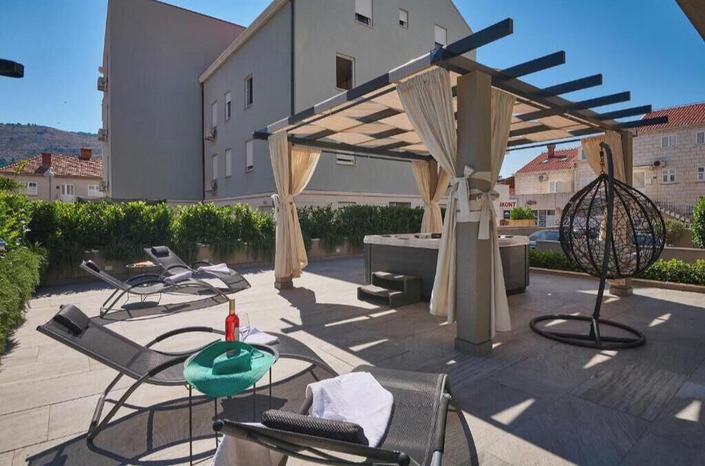 Un espacio al aire libre con sillones reclinables, una mesa y una pérgola con cortinas.