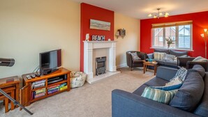 Ein Wohnzimmer mit Kamin, Fernseher, Sofa und Bücherregal.