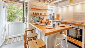 A kitchen with a wooden island, stools, a microwave, and a stove. - 1 Bed in Brixham (oc-bx020) (Brixham)