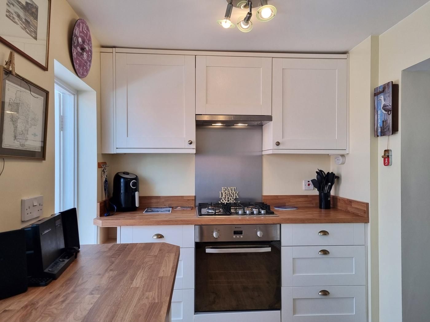 A compact kitchen with white cabinets, a built-in oven, a gas stove, and a coffee maker.