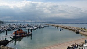 Una marina con imbarcazioni ormeggiate, un molo e un muretto frangiflutti in pietra.