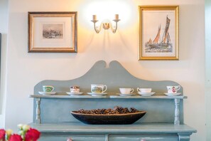 Una mesa de comedor con un cuenco de piñas, una lámpara de pared y dos cuadros enmarcados.