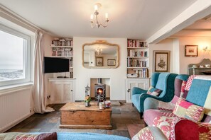 Una sala de estar acogedora con chimenea, estanterías, televisor y una zona de estar confortable.
