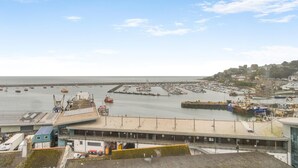 En småbåtshamn vid kusten med båtar, en brygga och en byggnad med ett sluttande tak.