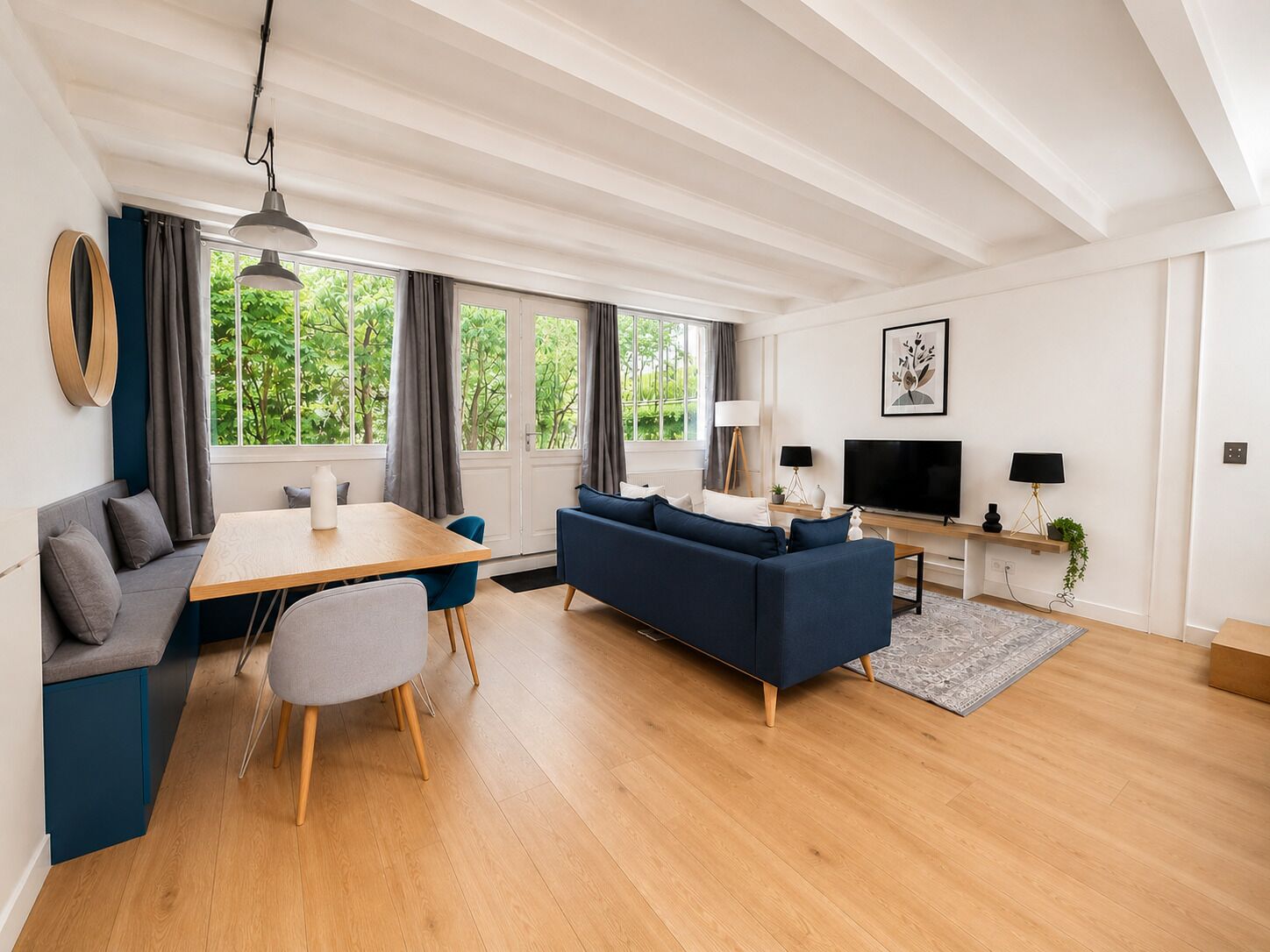 Een moderne woonkamer met een bank, eettafel en televisie.