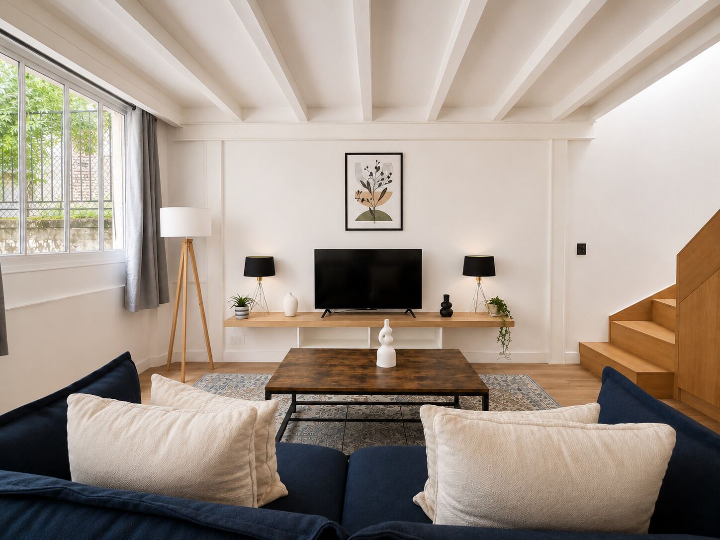 A modern living room with a television, two lamps, a coffee table, and a sofa.