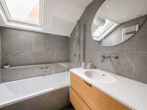 Een moderne badkamer met een badkuip, douche, wastafelmeubel en een spiegel.