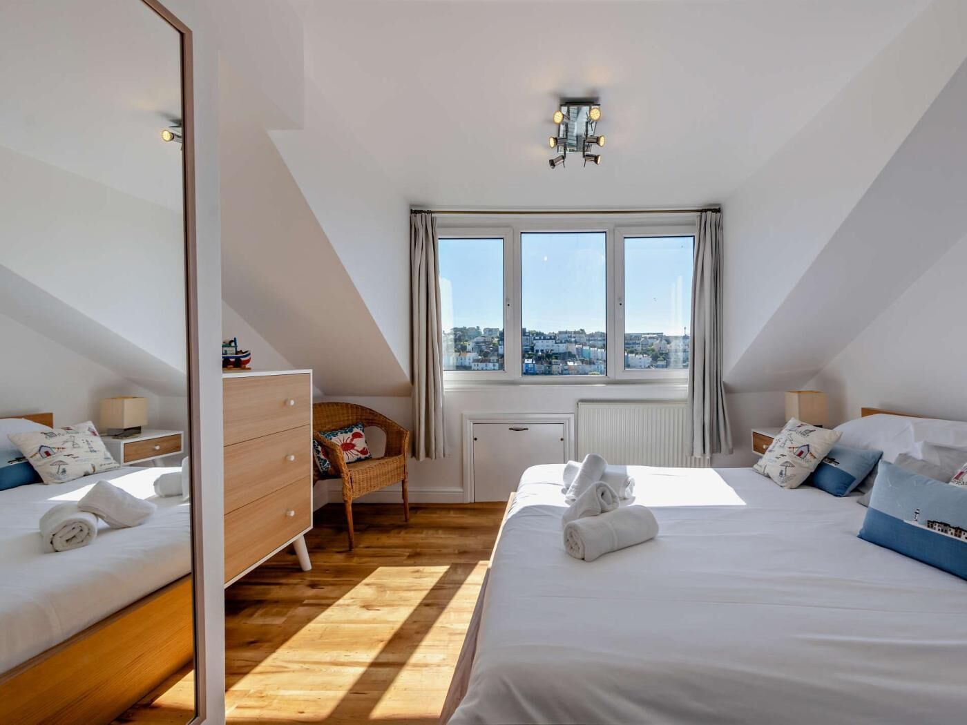 A bedroom with two beds, a dresser, a chair, a window with a view, and a ceiling light.
