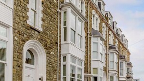 A row of terraced houses with white window frames and stone facades. - 2 Bed in Ilfracombe (oc-caps8) (Ilfracombe)