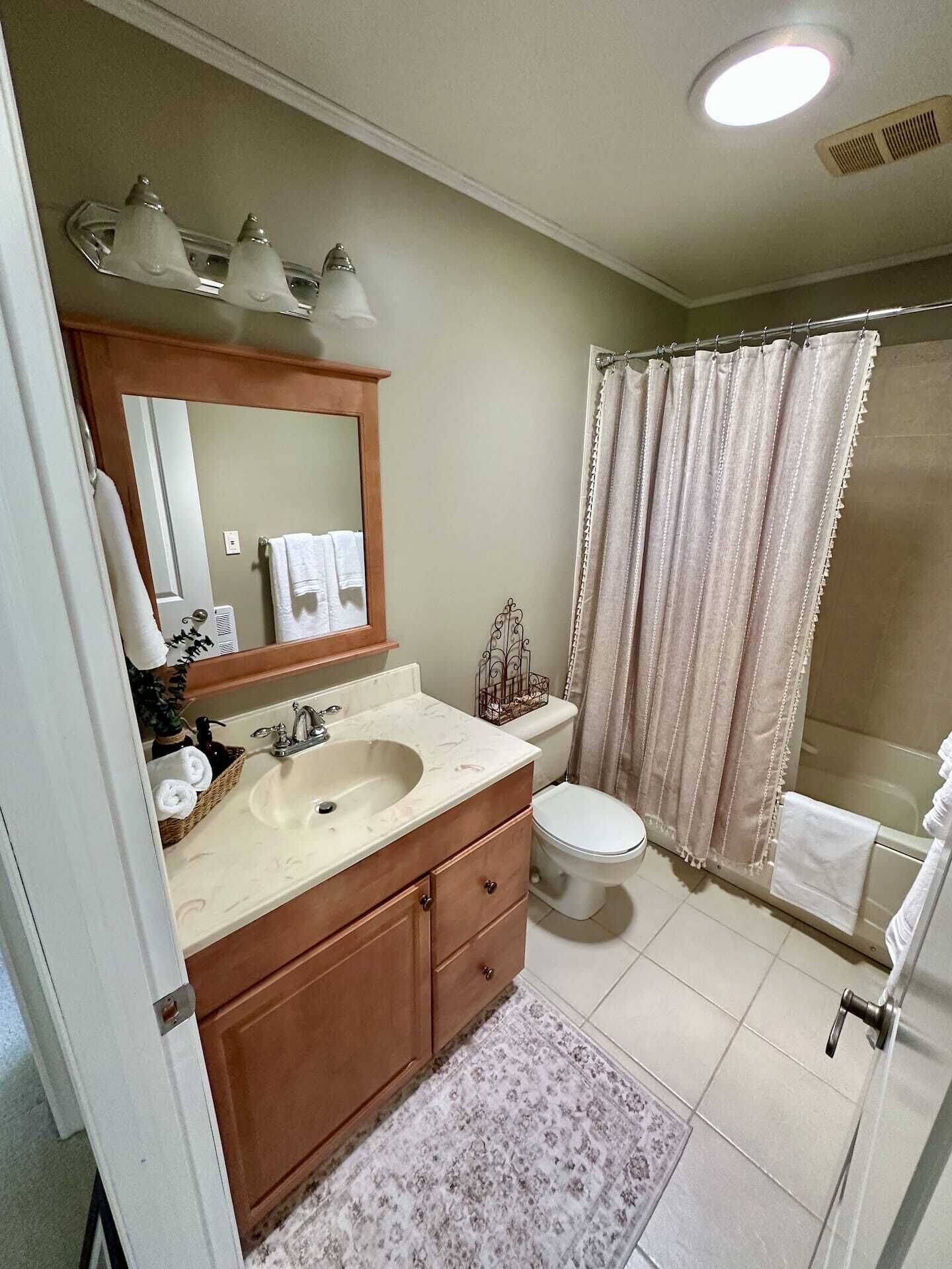 A bathroom with a double sink vanity, a toilet, a shower with a curtain, and a mirror above the sink.