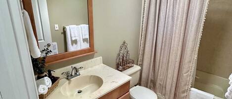A bathroom with a double sink vanity, a toilet, a shower with a curtain, and a mirror above the sink.
