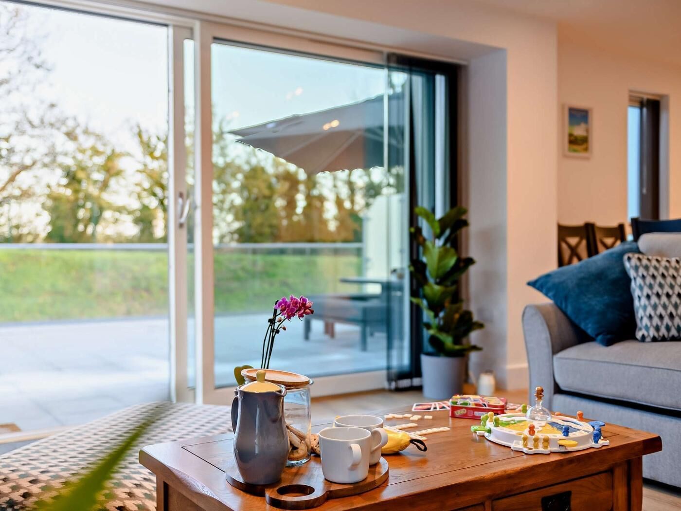 Ein modernes Wohnzimmer mit Couch, Couchtisch und einer großen Schiebeglastür, die zu einem Außenbereich führt.