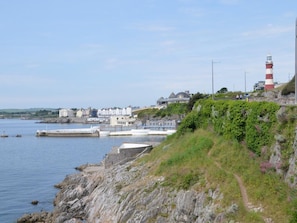 A coastal town with a lighthouse, stone buildings, and a rocky shoreline. - 2 Bed in Plymouth (oc-93195) (Plymouth)