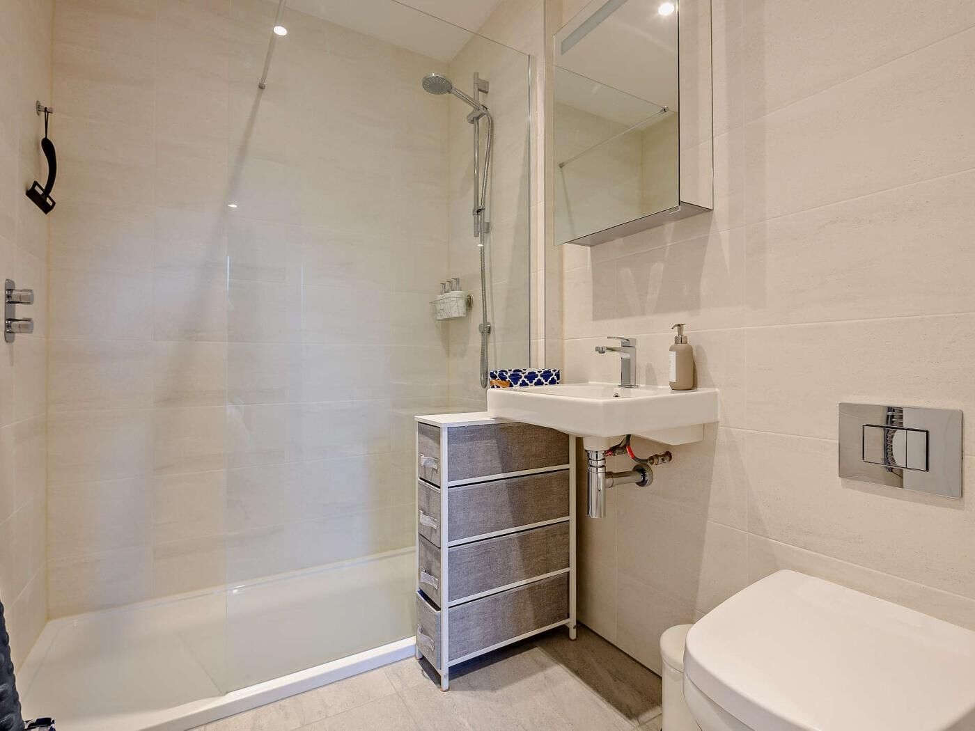 A modern bathroom with a glass-enclosed shower, a white sink, and a toilet.
