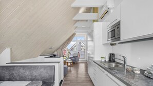Et moderne køkken med indbygget mikroovn, vask og spiseplads med bænk og bord.