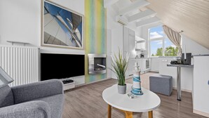 En moderne stue med en grå sofa, et hvidt sofabord og et fjernsyn.