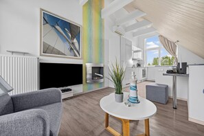 Ein modernes Wohnzimmer mit einem grauen Sofa, einem weißen Couchtisch und einem Fernseher.