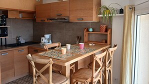 Eine Küche mit Holzausstattung, einer Kaffeemaschine und einem Esstisch mit Stühlen.